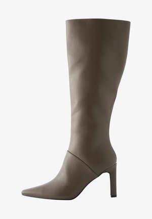 Botte en cuir marron à hauteur de genou avec un bout pointu et un talon aiguille, présentant une texture lisse et un design minimaliste.