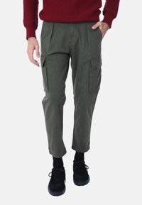Pantaloni cargo in cotone verde oliva, con tasche laterali e una vestibilità comoda. Abbinati a scarpe nere e calzini scuri.