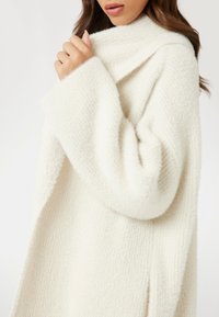 Witte comfortabele cardigan met een textuurrijke, donzige uitstraling. Voorzien van brede mouwen en een sjawlboord voor een ontspannen pasvorm.