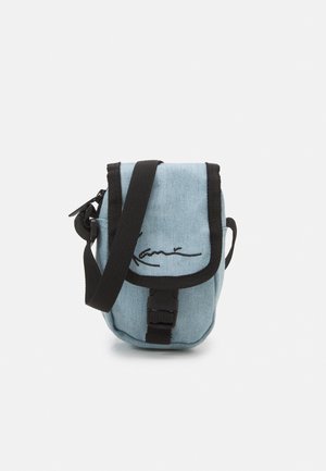 Petit sac bandoulière en tissu bleu clair avec bordure noire, bandoulière réglable, fermeture par boucle à l'avant et texte noir en écriture cursive sur le rabat avant.