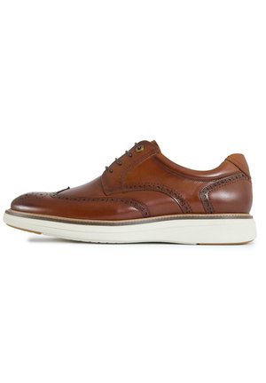 Brown leather brogue shoe with wingtip detailing, black laces, and white rubber sole, shown in side profile on white background.