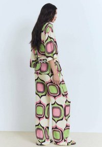 Gemustertes Loungewear-Set mit einem Oberteil und weit geschnittenen Hosen in Creme, Pink und Grün, versehen mit auffälligen geometrischen Formen und einem lässigen Schnitt.