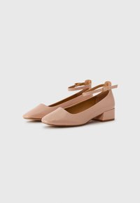 Pink patent leather ballet flats with a low block heel, almond-shaped toe, and ankle strap featuring a metal buckle. Smooth texture.