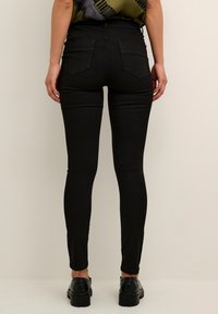 Svarta skinny jeans i denim med medelhög midja, två bakfickor och en jämn textur med lätt stretch.