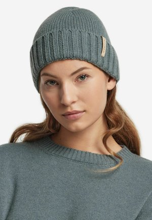 Grå strikbeanie med lodret ribbet mønster, udstyret med et syet mærke. Modellen bærer en matchende grå sweater med rund halsudskæring.