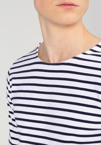 Marineblauw en witte gestreepte T-shirt van katoen, met een ronde hals en korte mouwen. De stof is zacht met een gladde textuur.