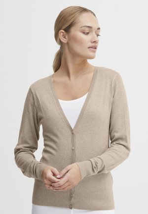 Beige cardigan made of soft knit fabric, featuring a V-neck, button front, and ribbed cuffs and hem. Worn over a white top.