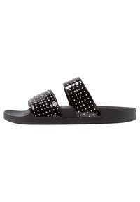 Des sandales noires à glissière avec deux larges brides ornées de clous brillants. Le matériau supérieur est brillant, tandis que la semelle est mate et texturée.