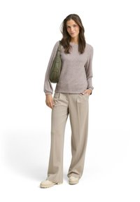 Gebreid lichtpaars sweater met een geometrisch patroon, gecombineerd met beige wijde broek en crèmekleurige plateau-schoenen. Houdt een groene schoudertas vast.