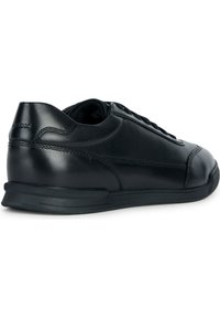 Černé kožené tenisky s kulatou špičkou, jemnými detaily prošívání a texturovanou podrážkou. Obsahují zavazovací konstrukci a polstrovanou vnitřní podšívku.