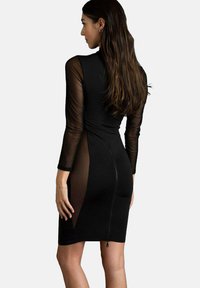 Abito nero con maniche lunghe trasparenti, design aderente e chiusura con zip sul retro. Presenta pannelli laterali in rete e una texture liscia.