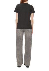 Zwarte katoenen t-shirt, korte mouwen, gecombineerd met hooggevoerde, losse grijze jeans met lichte vervaging en achterzakken.