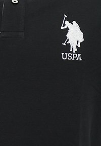 Polo nero con colletto, dotato di un logo ricamato bianco di un cavallo e cavaliere. Realizzato in materiale di cotone testurizzato.