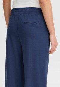 Pantalon bleu marine à coupe décontractée avec une taille élastique, doté d'une poche arrière unique et d'une texture lisse.