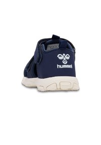 Mörkblå barnskor med två kardborreband, en texturerad gummisula och en vit logotyp på hälen. Överdel i syntetmaterial.