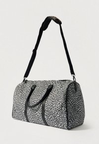 Saco de viagem preto e branco com padrão abstrato texturizado, duas pegas, alça ajustável e detalhes robustos em metal.