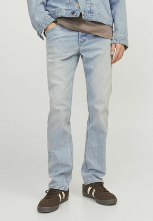 Light blue denim jeans with a straight-leg cut, featuring fading and five-pocket design, paired with brown sneakers.