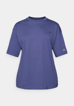 T-shirt de algodão roxa com decote redondo e mangas curtas, apresentando um pequeno logótipo no peito e um emblema no braço.
