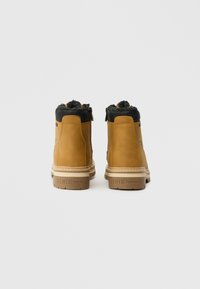 Tan læder ankelstøvler med en sort faux fur krave, som har en lynlås i siden og en beige gummisål. Brandet "DENIM TOM TAILOR" på hælen.