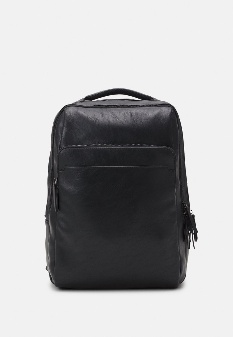 Sac à dos rectangulaire en cuir noir avec une poignée supérieure, une poche avant zippée et des fermetures éclair latérales supplémentaires, présenté sur un fond blanc.