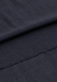 Tmavě námořnická látka s texturovaným povrchem, vykazující surový okraj. Materiál se zdá být mírně hrubý a tkaný, bez jasného vzoru.