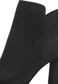 Stivale alla caviglia nero con texture, tacco a blocco, pannello elastico laterale e design affusolato.