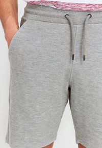 Shorts en mélange de coton gris avec une taille élastique, dotés de poches latérales et d'une fermeture à cordon. Texture lisse avec un motif subtil et uniforme.