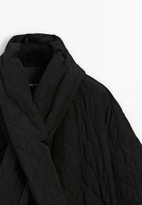 Black quilted jacket with diamond stitching and a wide, padded lapel collar on a white background.