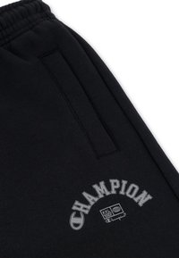 Zwarte sweatpants met een trekkoord in de taille, voorzien van een zijzak en een grijs "CHAMPION" logo met aanvullende merkdetails.