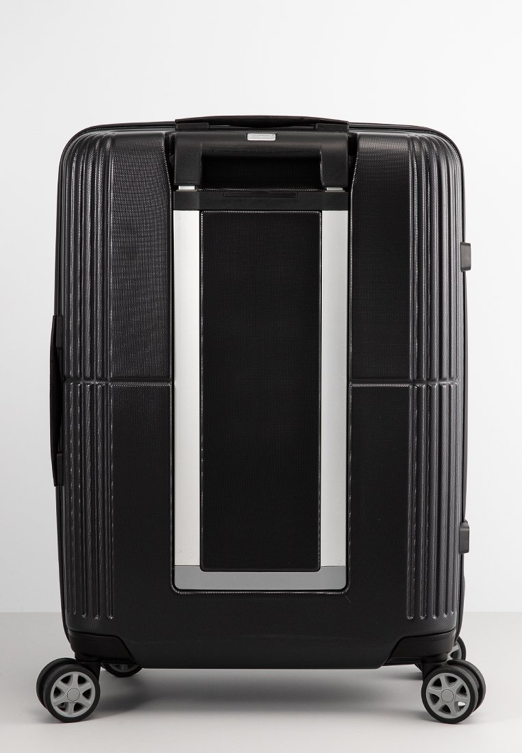 Black hard-shell suitcase with horizontal grooves, silver accents, dual wheels, and a retractable handle. Smooth texture with secure closure.