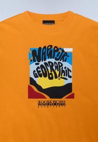 Orange Baumwoll-T-Shirt mit einem bunten grafischen Design, das die Worte "Napapijri Geographic" zeigt. Das Design umfasst blaue, gelbe und schwarze Elemente.