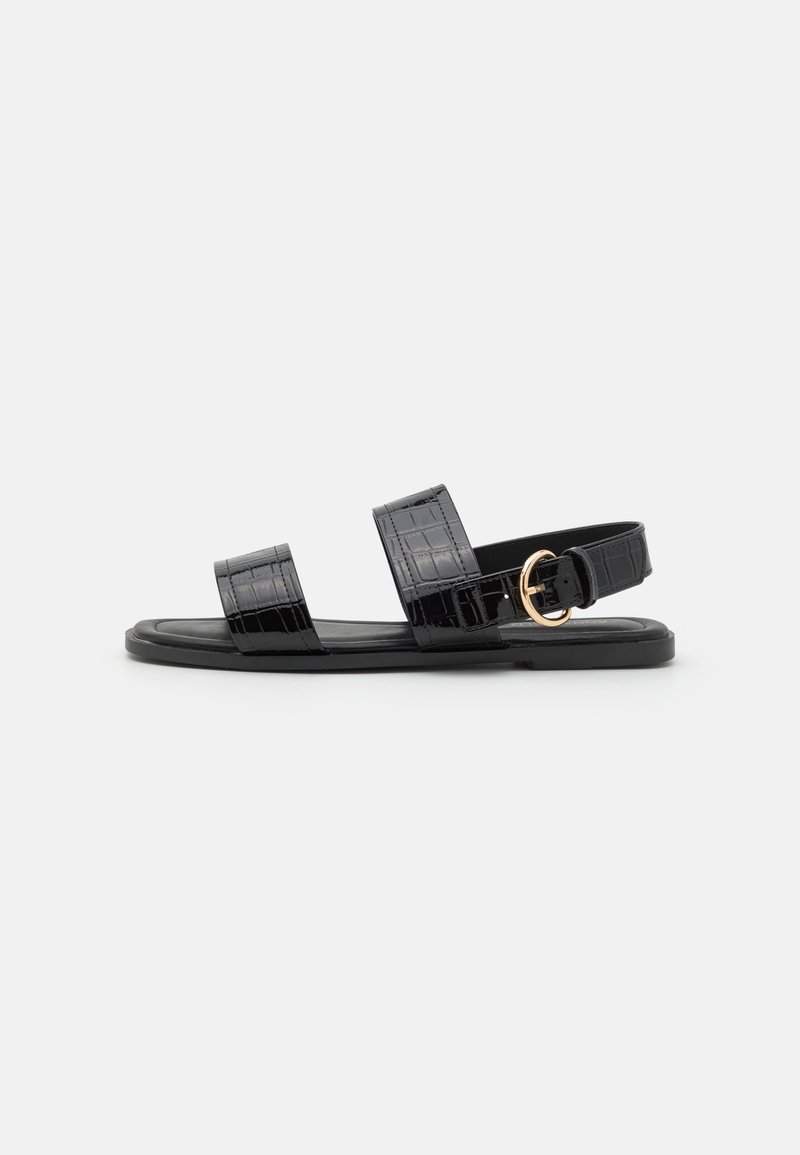 Svarta sandaler i konstläder med krokodilmönster, två breda remmar och detalj med guldspänne. Platt sula, minimalistisk design.