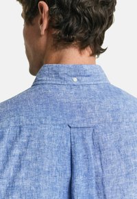 Lichtblauw button-up shirt met een gestructureerde stof, rug yoke met plooidetail en een ronde kraag.