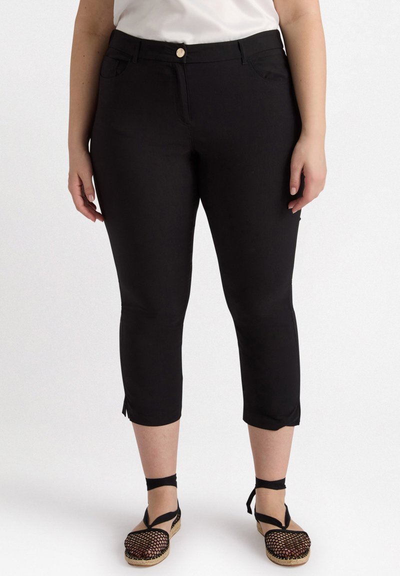 Zwarte capri-broek van gladde stof met een getailleerde snit, voorzien van twee frontzakken en een knoopsluiting. De zoom heeft zij-splitjes.