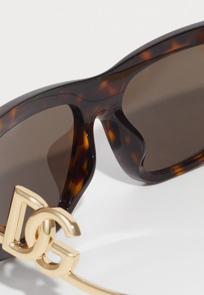 Tortoiseshell sunglasses with dark lenses and gold intertwined "DG" logo hinge detail on white background.