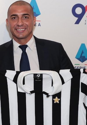 Zwart-wit gestreepte voetbalshirt met een klassieke kraag, voorzien van een gouden sterembleem aan de linkerkant.