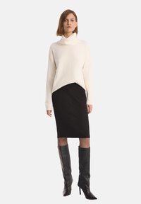 Kremowy sweter z dekoltem w łódkę, w połączeniu z czarną prążkowaną spódnicą ołówkową. Całość dopełniają czarne kozaki za kolano na wysokim obcasie.