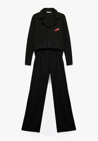 Sort loungewear sæt bestående af en skjorte med knaplukning og bukser med vidde. Har en chili-peber broderi detalje på skjorten. Blød stoftekstur.