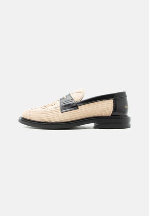 Mocasín beige tejido con ribete de cuero negro, puntera redondeada, suela negra y patrón decorativo cosido en la parte superior.