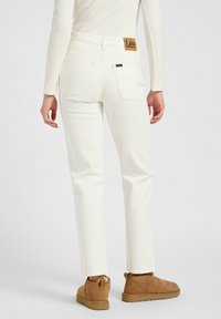 Jeans de mezclilla blanca con un diseño liso, que cuentan con un parche de cuero marrón con el logo de Lee en la parte posterior de la cinturilla y dos bolsillos traseros.