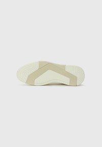 Shoe sole in light beige with textured patterns, featuring a wavy design and rubber grip, showcasing various shades of cream and taupe.