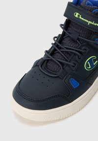 Granatowe sneakersy typu high-top z gładkiej skóry, niebieskimi akcentami, teksturowanym językiem i perforowanym noskiem dla lepszej wentylacji.