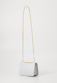 Borsa a tracolla bianca in pelle con catena dorata, forma rettangolare, bordi leggermente arrotondati e texture liscia. Presenta accessori decorativi.