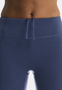 Dunkelblaue Sportleggings mit hoher Taille, ausgestattet mit einem Kordelzug und glatter Textur, die bis zum Knöchelschnitt verlaufen.