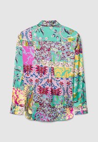 Chemisier multicolore pour femme présentant un design patchwork avec des motifs floraux et abstraits sur un fond turquoise, rose et jaune.