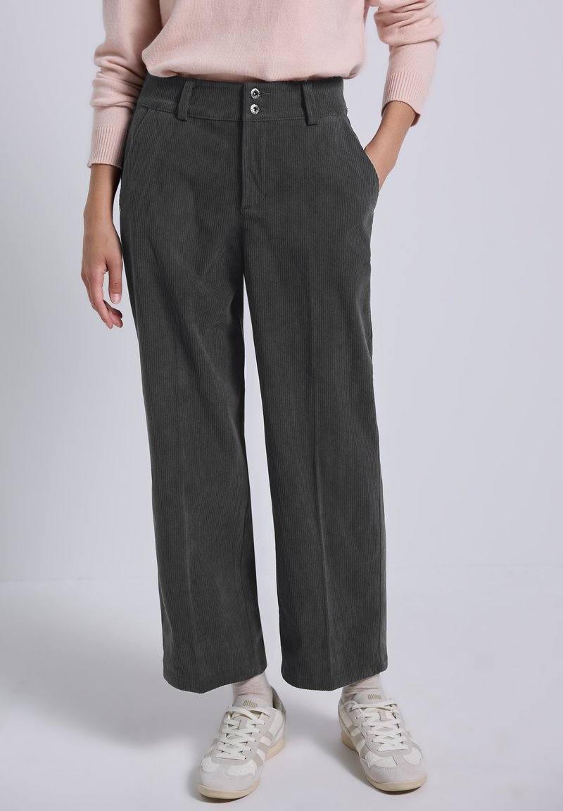 Pantaloni a gamba larga in corduroy grigio con due tasche anteriori e chiusura a due bottoni. Abbinati a sneakers chiare per un contrasto.