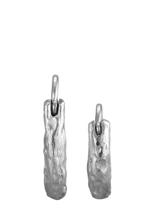 Deux boucles d'oreilles argentées allongées et texturées avec une surface polie. Elles présentent une attache en boucle simple et varient légèrement en taille.