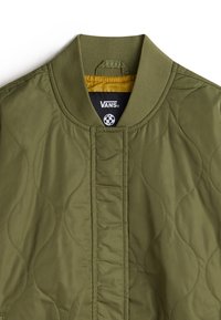 Quilted bomber jacket in olive green with ribbed collar, features a yellow lining and a prominent Vans logo on the interior.
