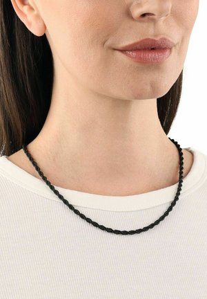 Collana nera intrecciata realizzata in materiale flessibile, caratterizzata da una superficie liscia e un design semplice. Indossata sopra una maglietta bianca a coste.