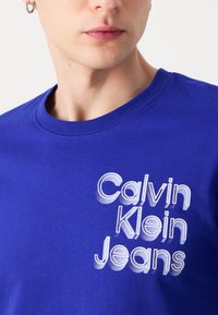 Calvin Klein Jeans STACKED EUPHORIC LOGO TEE - Camiseta estampada - sapphire blue